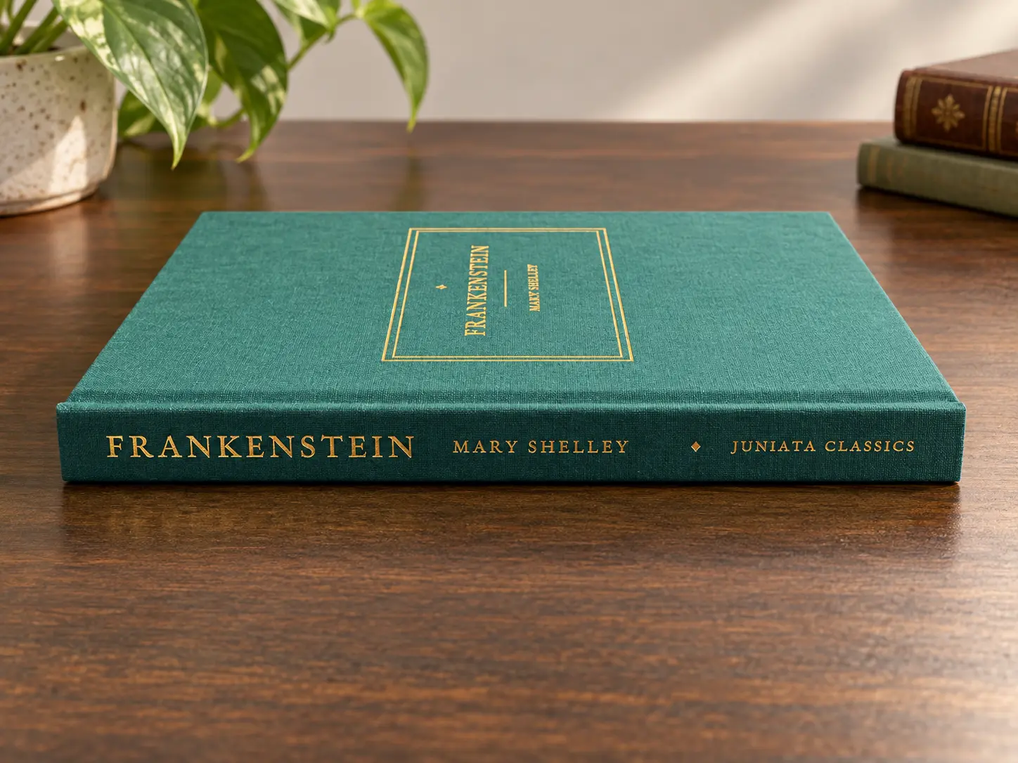 Teal clothbound Frankenstein by Mary Shelley with gold-lettered Juniata Classics spine on a wooden table